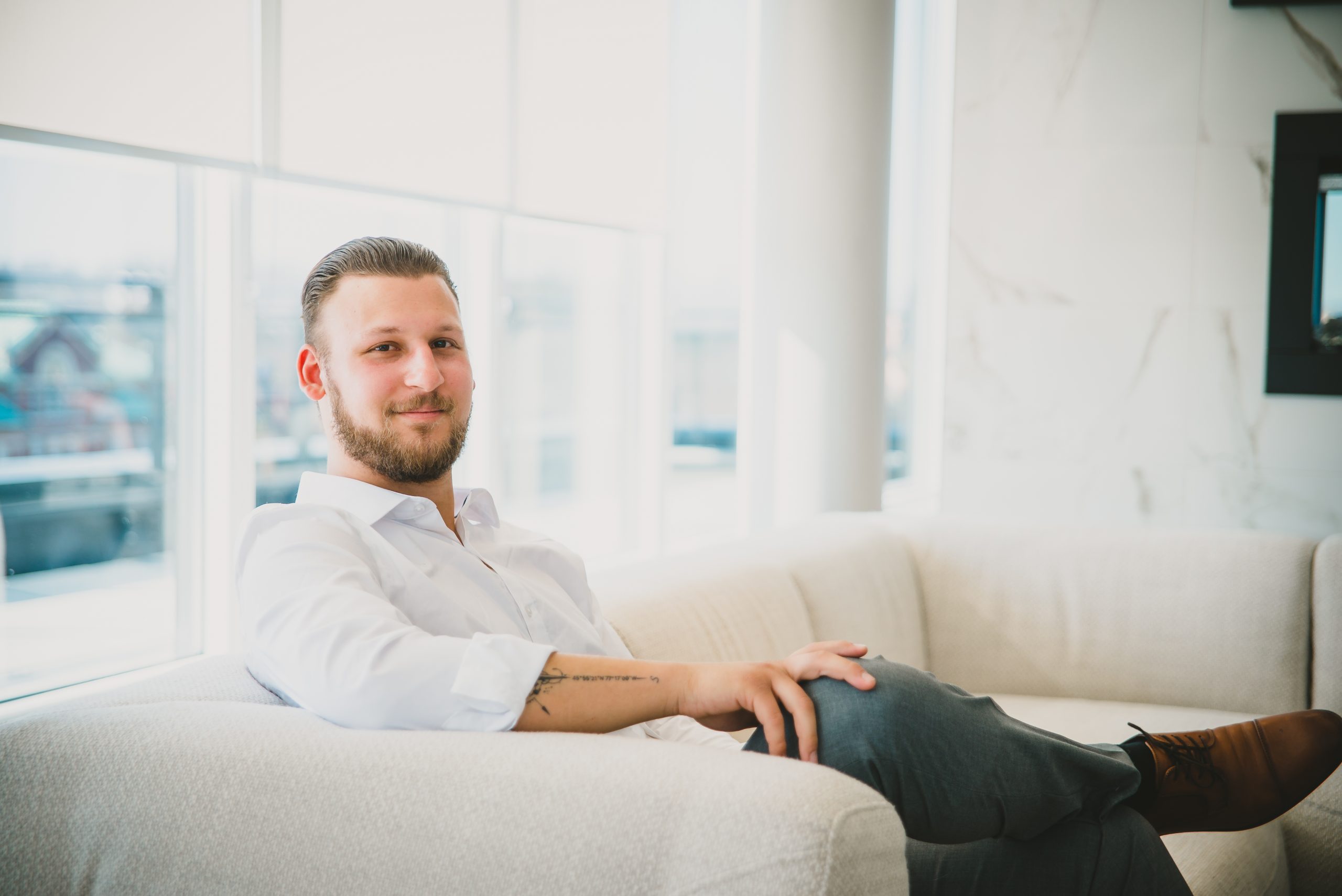 Photo of Arnold Gluck, Century 21 United REALTOR and your local REALTOR sitting on a cream couch looking at the camera.